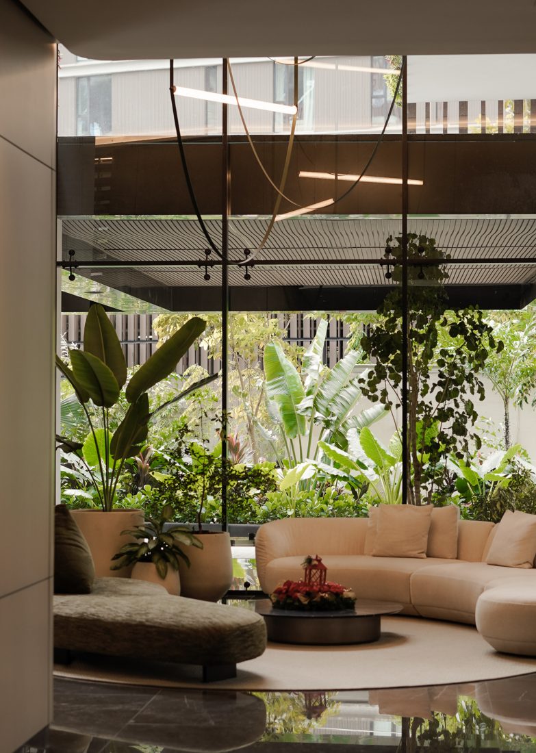 Lobby con sofás curvos, potes de lujo y jardín tropical al fondo